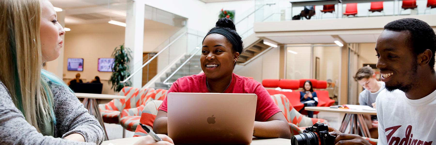 Three students work on a project while they sit at a table in the central commons, Franklin Hall.