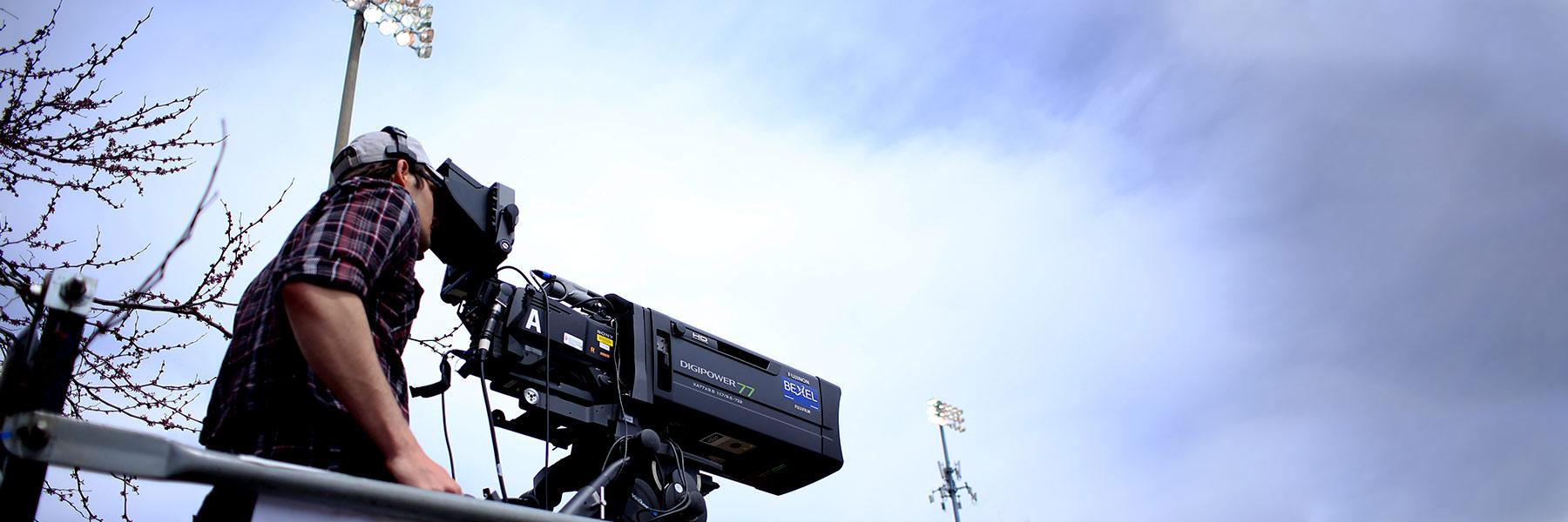 A student operates a TV camera outside.