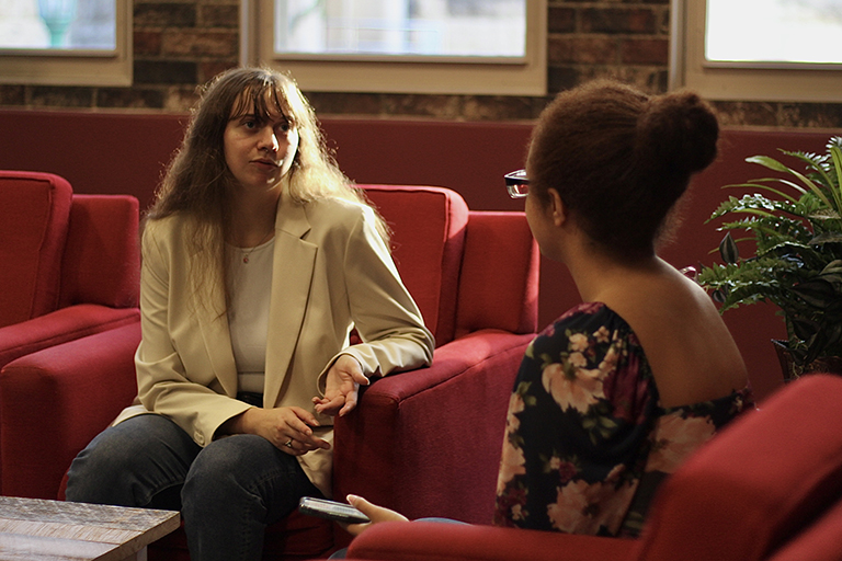 Two people seated in a studio talking to each other.