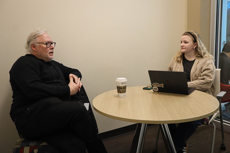Jason Wadler talks to Emerson Elledge at a table.