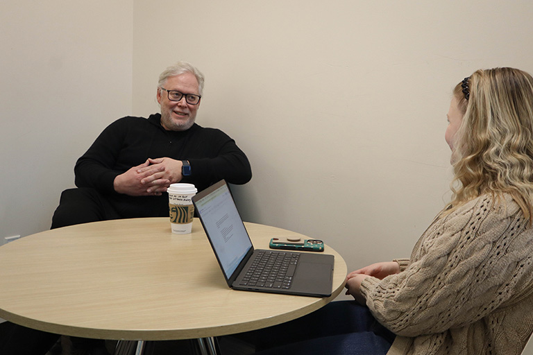 Jason Wadler talks to Emerson Elledge at a table.