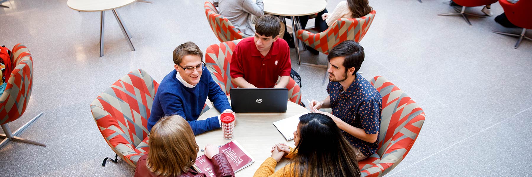 A group of students sit at a round table in The Commons of The Media School.